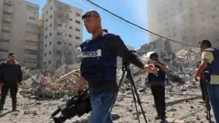 Jornalistas em destroços em Gaza