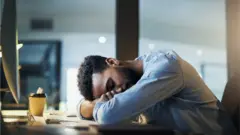 Un homme assoupi sur son bureau