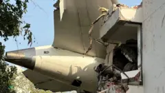 A cauda da aeronave aparece atravessando a lateral de um prédio