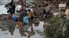 बाढीबाट प्रभावित मानिसहरू सामान खोज्दै