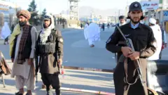 اثنان من أفراد الأمن التابعين لطالبان يحملان الأسلحة الخفيفة في أحد شوارع قندهار