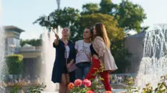 Parkda selfie çubuğu ilə şəkil çəkən insanlar