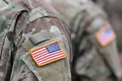 Ibendera ry'Amerika riri mu mwenda wa gisirikare w'Amerika wambawe n'umusirikare utaboneka mu maso. Inyuma ye hari undi musirikare na we utaboneka mu maso, wambaye umwenda wa gisirikare na wo uriho ibendera ririmo igihu n'umwenda we urimo igihu.