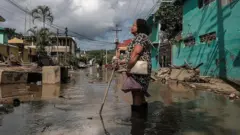 Una mujer intenta avanzar con el agua casi a la altura de las rodillas