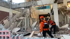 Emergency workers look through the rubble at Lauren Say port in Maumere