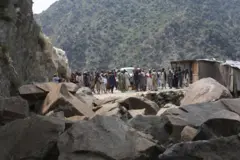 Unos hombres ante un camino bloqueado por piedras