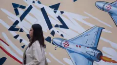 15 июня 2026 года молодая иранка проходит мимо настенной росписи в центре Тегерана, Иран