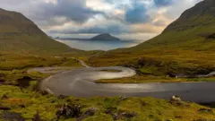 Estrada sinuosa com o mar e uma ilha ao fundo
