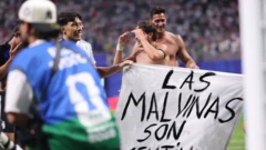 Unos jugadores argentinos en el campo, sin camisetas, sosteniendo una pancarta que dice "Las Malvinas son argentinas"
