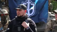 Denis Kapustin (uri hagati), akikijwe n'abarwanyi bo mu itsinda Russian Volunteer Corps, aganira n'abanyamakuru muri Ukraine. Ifoto yo ku itariki ya 24 Gicurasi (5) mu 2023 