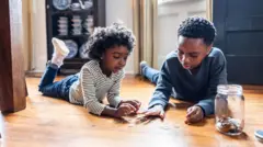 A boy and a girl counting change on floor at home
