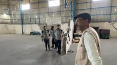 سامي مطر يصطحب صحفياً محلياً من بي بي سي في جولة في مستودع (أنيرا) الفارغ.