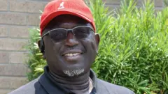 Charlton Roberson, de óculos e boné