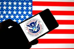 تصویر لوگوی وزارت امنیت داخلی ایالات متحده امریکا در مقابل پرچم این کشور 