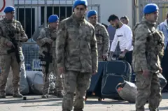 جنود أتراك على الحدود مع سوريا ينظمون عودة لاجئين سوريين إلى بلادهم بعد إطاحة المعارضة السورية بحكم بشار الأسد.