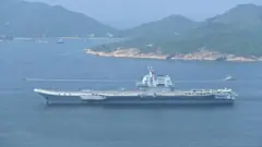 Aviones de combate y helicópteros estacionados en los puntos de despegue de la tradicional cubierta de vuelo de “salto de esquí” del segundo portaaviones de China, el Shandong, mientras navega por el Canal Lamma Oriental de Hong Kong.