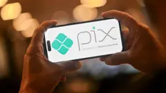 Pessoa segura celular com símbolo do Pix na tela