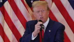 Donald Trump speaking in front of US flag