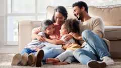 Happy family with two daughters hugging their mother and bonding at home.