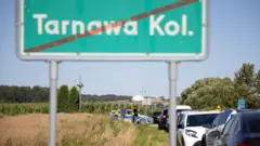 Znak drogowy z napisem „Tarnawa Kolonia” i samochody widoczne w pobliżu miejsca, gdzie po naruszeniu polskiej przestrzeni powietrznej spadł obiekt uznawany za rosyjski pocisk manewrujący. ZAKAZ DYSTRYBUCJI W POLSCE.