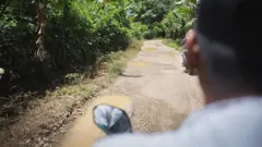 Un hombre en una moto recorre una vía no pavimentada en Colombia