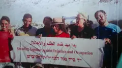 صورة أرشيفية عودة الهذالين وسط مجموعة من النشطاء يمسكون بيدهم لافتة كُتب عليها: يداً بيد ضد الظلم والاحتلال