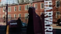 Отражение здания университета в витрине магазина, продающего вещи с символикой Гарварда.