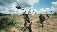 Soldados norte-americanos caminhando por um campo no Vietnã