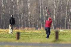 Trump de costas jogando golfe