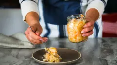 Uma mão coloca comida fermentada em um prato