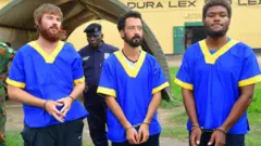 (De gauche à droite) Tyler Thompson, Benjamin Zalman-Polun et Marcel Malanga escortés par les services de sécurité à l'aéroport principal de Kinshasa. 