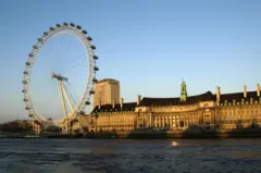 The London Eye (aka Millennium Wheel) and the former County Hall on the river Thames at sunset South Bank, London 2003