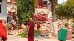 Pessoas vestindo mantos se reúnem perto de um templo desabado após o terremoto em Mandalay