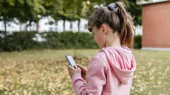 Menina olhando um telefone celular ao ar livre