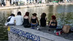 Devojke sede na zidiću na obali reke