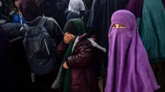 Suriye'deki Roj Kampında pembe burka içinde bir kız çocuğu fotoğrafçıya bakıyor