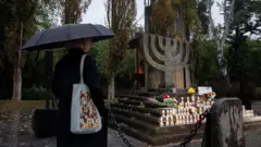 Жінка з парасолькою відвідує церемонію біля меморіалу Бабин Яр, присвячену 84-й річниці масових розстрілів мирних жителів, переважно євреїв, нацистами та їхніми колабораціоністами під час Другої світової війни, у Києві, вересень