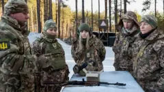 Itsinda ry'abasirikare b'abakorerabushake b'abagore bari mu myitozo yo kurasa, aha ni mu mujyi wa Bucha muri Ukraine. Bose bambaye imyenda yijimye ndetse bazengurutse imbunda iri ku meza iriho urubura. 