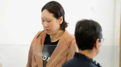 Hakyung Lee, wearing a brown jacket over a black shirt, is shown in court in this file photo from 2022