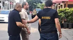 Полицейские ведут журналиста Афгана Садыгова по улице