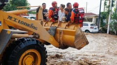 Люди в ковше дорожной машины над потоком воды