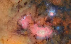 As nuvens de gás e poeira rosa, azul e laranja que compõem a nebulosa de Trífida e a nebulosa da Lagoa