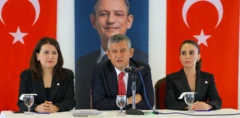 Özel yanında iki yeni partili kadın vekille masada oturarak konuşuyor. Arkada Türk bayrakları ve kendi gülen fotoğrafı var.