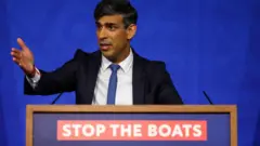 Sunak gesticulando em discurso; na frente, no palanque, aparece frase: Stop the boats (Parem com os barcos)