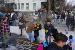Manifestantes roceados con una sustancia amarilla por parte de la policía en la zona donde fue asesinada una mujer en Mineápolis. Es una multitud que se trata de proteger de la sustancia. Los agentes llevan su uniforme. Hay nieve en el suelo.