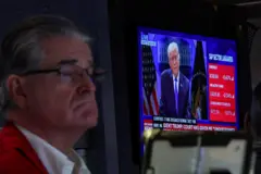 Operador da bolsa trabalha no pregão enquanto um telão exibe o presidente dos Estados Unidos, Donald Trump, durante uma entrevista coletiva sobre as tarifas