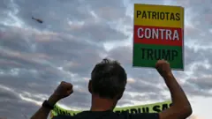 Homem segura placa com os dizeres 'Patriotas contra Trump' em prostesto