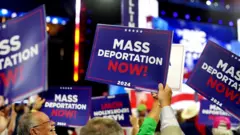 Simpatizantes de Trump seguram cartazes durante evento da campanha presidencial onde se lê: "Deportações em massa já"