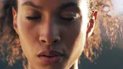 Mulher com os olhos fechados em um momento de introspecção