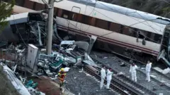 Vagones de tren yacen sobre la vía férrea tras el accidente en España, mientras investigadores examinan los escombros